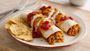 Enchilada Tortillas with seasoned beef, steak, chicken, pork  or grilled vegetables, rolled with refried beans and topped with chese, Arriba enchilada sauce and sour cream